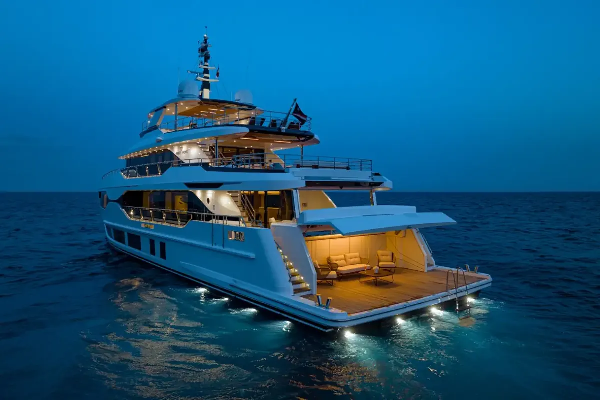 Majesty 120 at dusk with its stern and beach club lit up